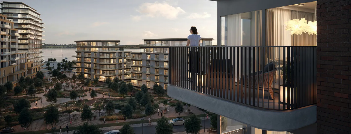 Modern waterfront residential complex with landscaped courtyards, multiple mid-rise buildings, and a person standing on a balcony overlooking the view – part of a luxury construction project portfolio.